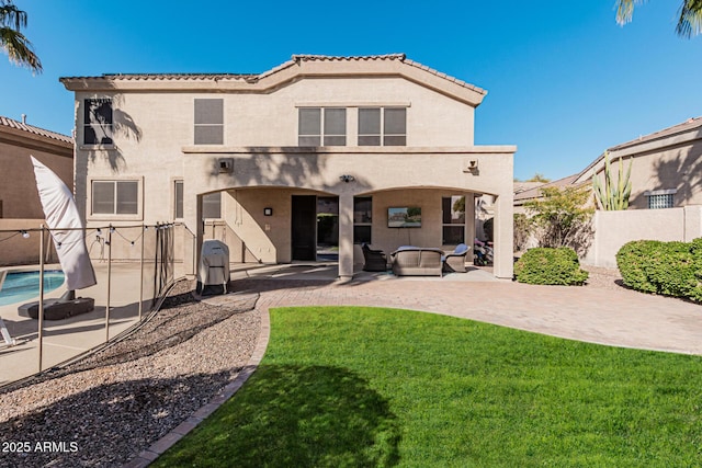 rear view of property featuring a fenced in pool, a lawn, outdoor lounge area, and a patio