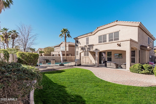 rear view of property with a fenced in pool, a lawn, and a patio