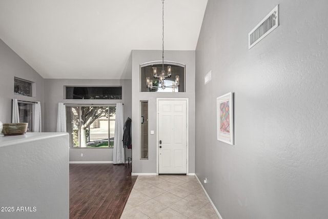 entrance foyer featuring high vaulted ceiling, a chandelier, and light hardwood / wood-style floors