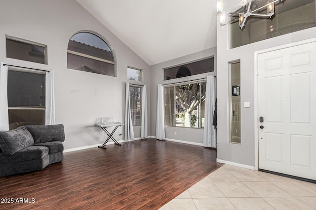 entrance foyer featuring wood-type flooring, high vaulted ceiling, and a chandelier