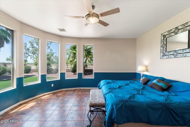 bedroom featuring multiple windows, dark tile floors, and ceiling fan