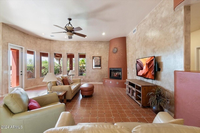 tiled living room with ceiling fan and a fireplace