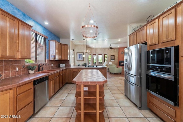 kitchen with a center island, stainless steel appliances, tile countertops, sink, and tasteful backsplash