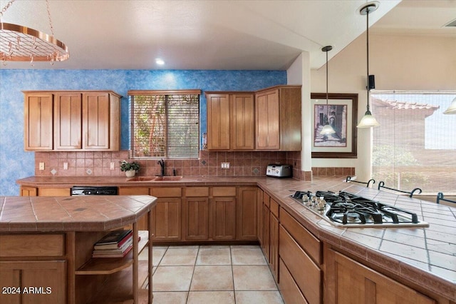 kitchen featuring decorative light fixtures, backsplash, tile counters, sink, and light tile floors