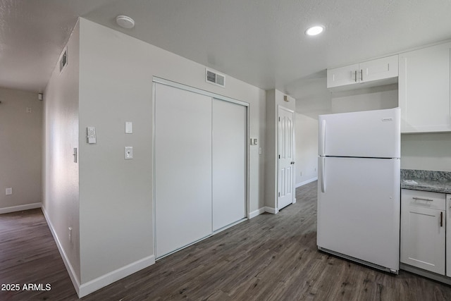 kitchen with white cabinetry, white refrigerator, and dark hardwood / wood-style flooring