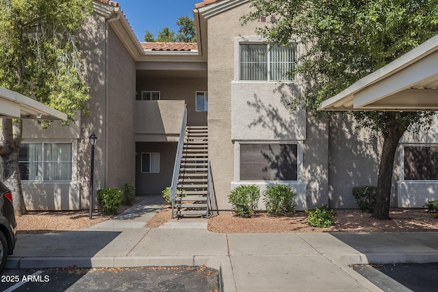 exterior space with stucco siding, a tile roof, and stairway