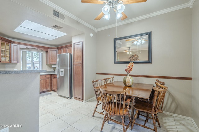 dining space featuring light tile patterned floors, baseboards, a ceiling fan, and visible vents