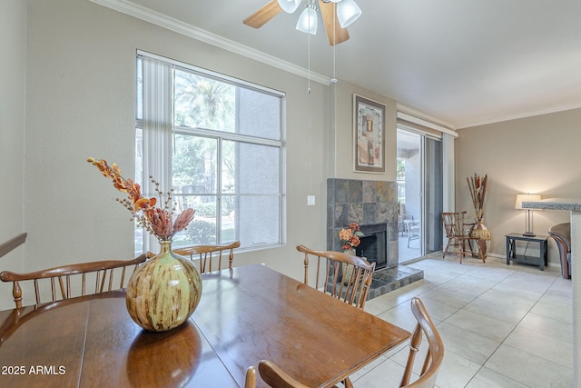 dining area with crown molding, ceiling fan, light tile patterned floors, and a fireplace