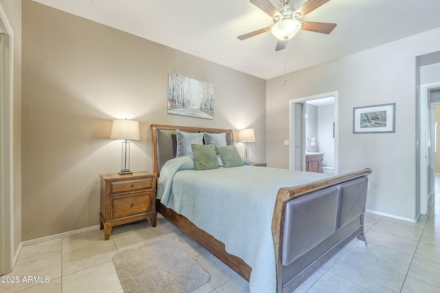 bedroom featuring baseboards, light tile patterned floors, and ensuite bath