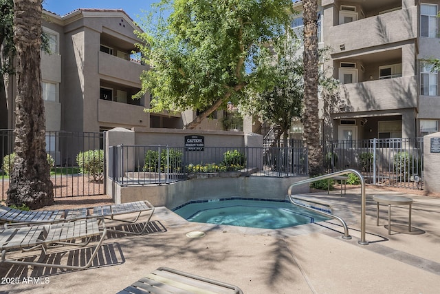 view of swimming pool featuring a hot tub and fence