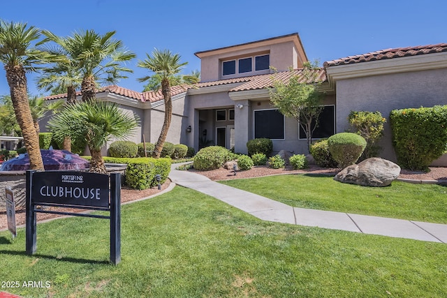mediterranean / spanish-style house featuring a front lawn, a tile roof, and stucco siding