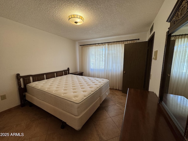 bedroom featuring a textured ceiling, visible vents, and tile patterned flooring