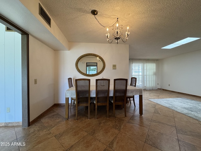 dining space with visible vents, baseboards, a textured ceiling, a notable chandelier, and a skylight