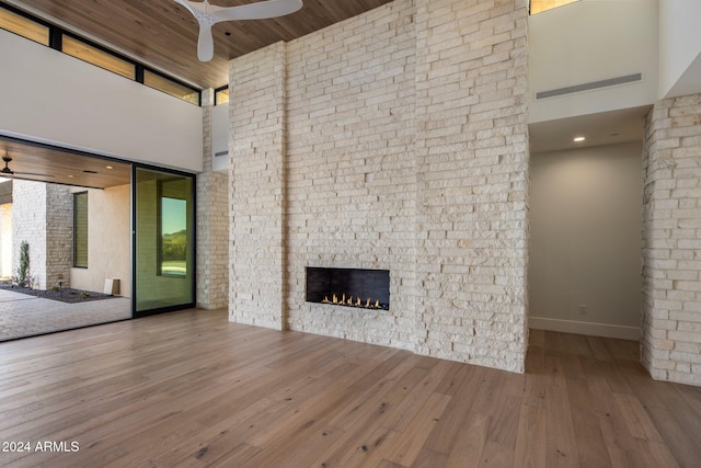 24779 N 91st St, Scottsdale, AZ 85255 - unfurnished living room with a towering ceiling, a lit fireplace, ceiling fan, wood finished floors, and baseboards