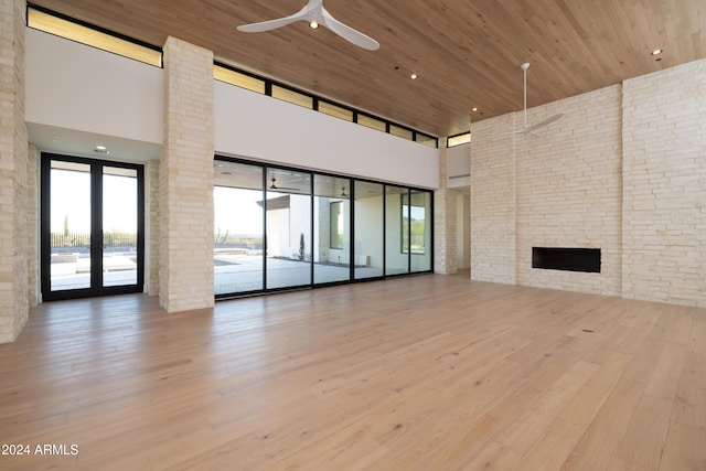 unfurnished living room with wood ceiling, ceiling fan, light hardwood / wood-style floors, and a high ceiling