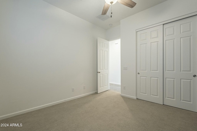 unfurnished bedroom featuring ceiling fan, light colored carpet, and a closet