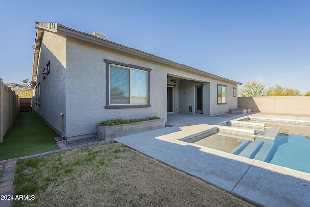 rear view of property featuring a patio area, a fenced in pool, and a yard