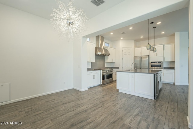 kitchen featuring a center island with sink, premium appliances, white cabinetry, and wall chimney range hood