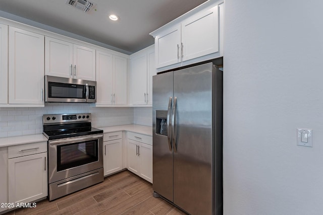 kitchen featuring visible vents, appliances with stainless steel finishes, light countertops, white cabinetry, and backsplash