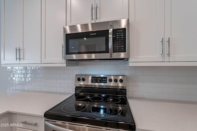 kitchen with white cabinetry, appliances with stainless steel finishes, decorative backsplash, and light stone counters