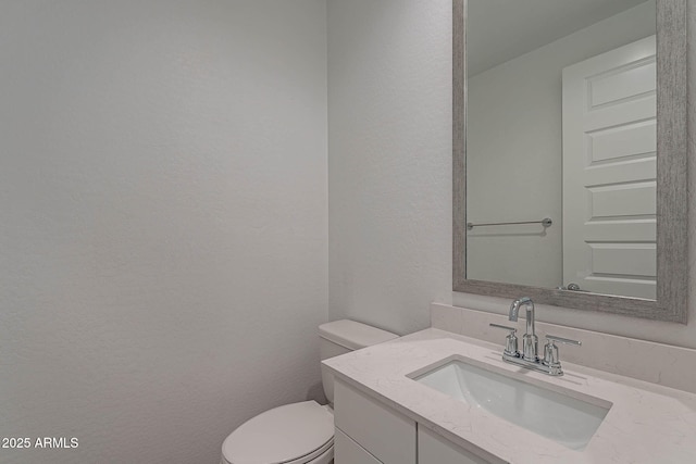 bathroom featuring a textured wall, vanity, and toilet