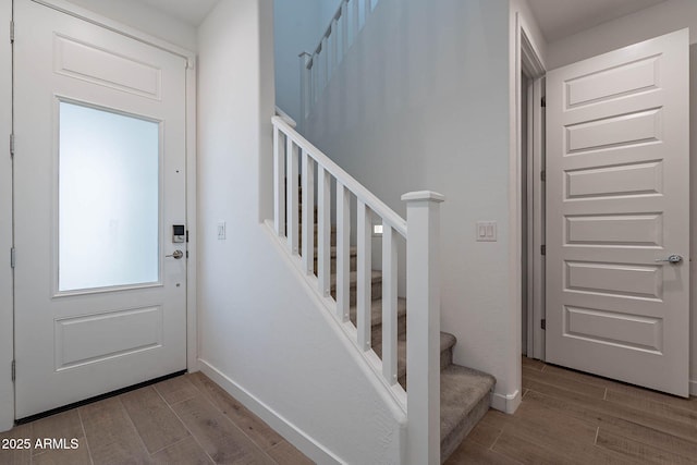 entryway with stairway, baseboards, and wood finished floors