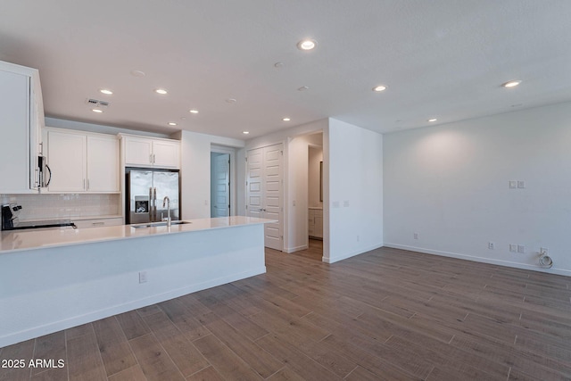 kitchen featuring a peninsula, a sink, visible vents, appliances with stainless steel finishes, and dark wood-style floors