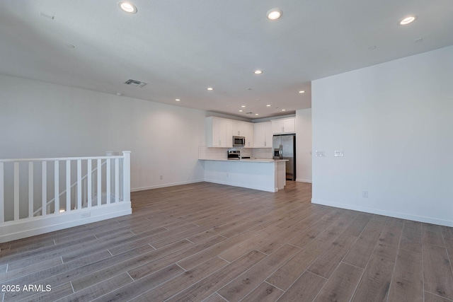 unfurnished living room with baseboards, visible vents, wood finished floors, and recessed lighting