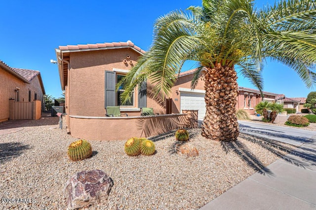 view of front of home with stucco siding, fence, a garage, and a tile roof