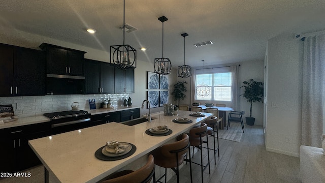 kitchen featuring sink, a breakfast bar, a kitchen island with sink, and decorative light fixtures