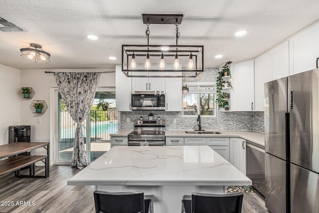 325 E Harmony Ave, Mesa, AZ 85210 - kitchen with appliances with stainless steel finishes, tasteful backsplash, wood finished floors, white cabinetry, and a textured ceiling