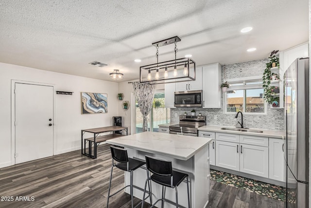 325 E Harmony Ave, Mesa, AZ 85210 - kitchen featuring stainless steel appliances, tasteful backsplash, dark wood finished floors, white cabinetry, and a textured ceiling