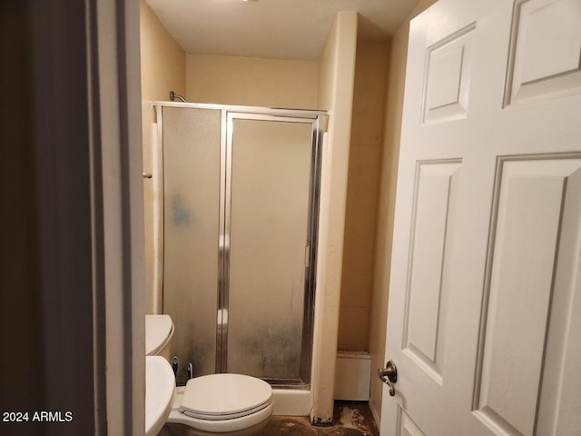 bathroom featuring toilet and a shower with shower door