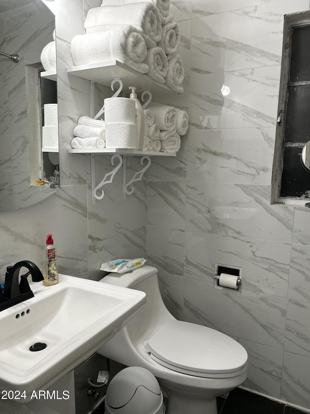 bathroom with tile walls, toilet, and sink