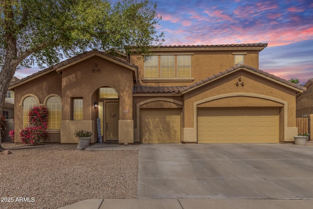 mediterranean / spanish house featuring stucco siding, an attached garage, driveway, and a tile roof