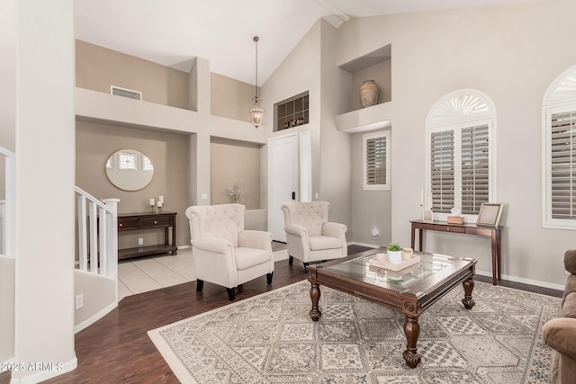 living room with visible vents, baseboards, stairs, wood finished floors, and high vaulted ceiling