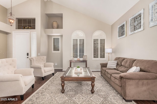 living area with wood finished floors, baseboards, and high vaulted ceiling