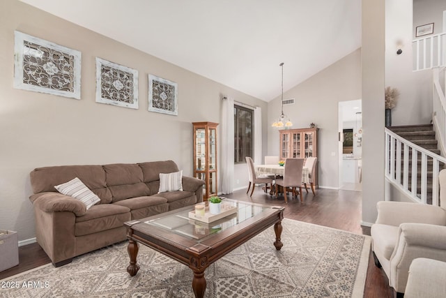 living area featuring stairway, a notable chandelier, wood finished floors, and high vaulted ceiling