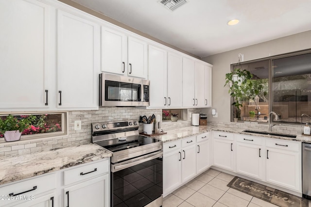 kitchen featuring visible vents, a sink, backsplash, stainless steel appliances, and light tile patterned flooring