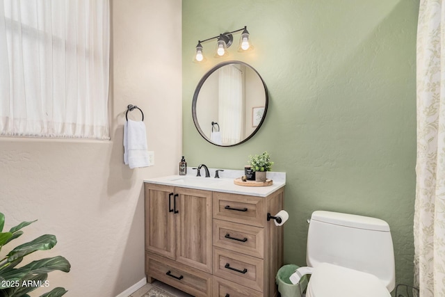 bathroom featuring baseboards, toilet, and vanity