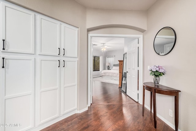 hallway featuring dark wood-type flooring and baseboards