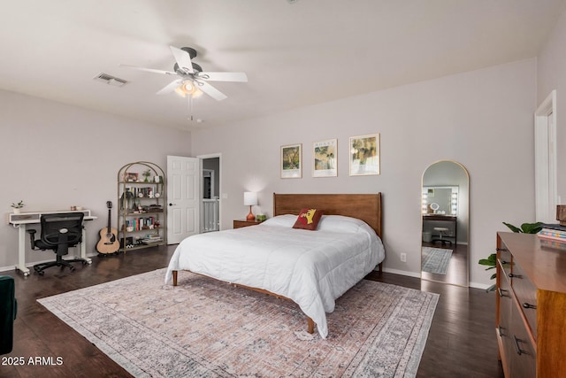 bedroom with baseboards, visible vents, arched walkways, ceiling fan, and dark wood-type flooring