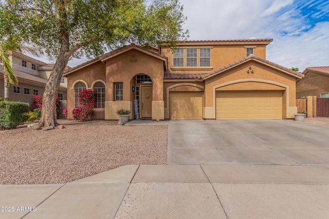 mediterranean / spanish-style home featuring fence, an attached garage, stucco siding, concrete driveway, and a tiled roof