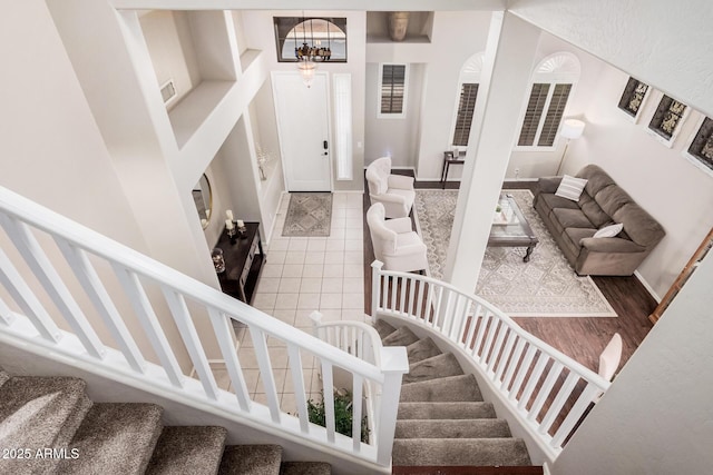 stairway featuring tile patterned flooring, baseboards, and an inviting chandelier