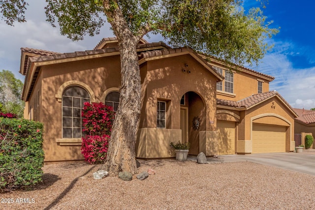 mediterranean / spanish house featuring a tile roof, a garage, driveway, and stucco siding