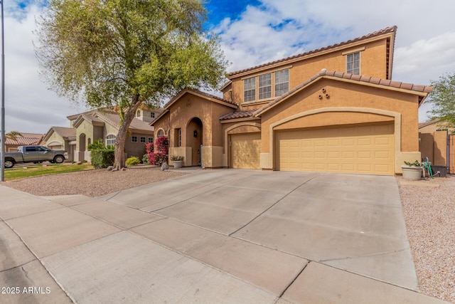 mediterranean / spanish-style home featuring stucco siding, driveway, a tile roof, and an attached garage