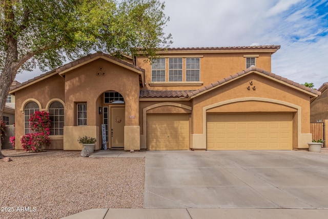 mediterranean / spanish home featuring a tile roof, driveway, and stucco siding