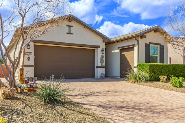 view of front of house featuring a garage, a tile roof, driveway, and stucco siding