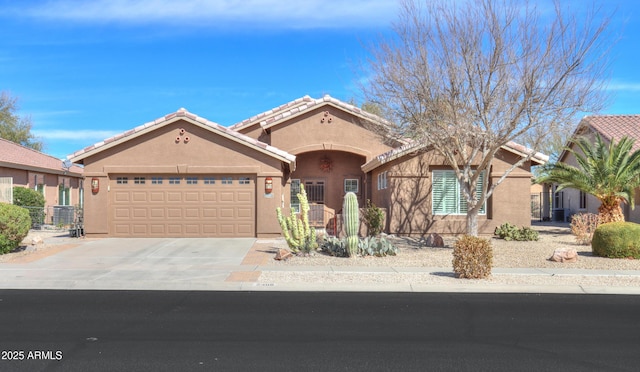 mediterranean / spanish-style home with a garage, concrete driveway, a tiled roof, and stucco siding