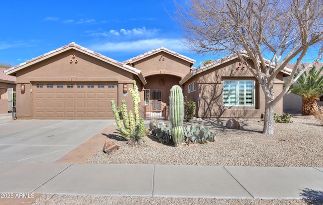 view of front of property with driveway, an attached garage, a tile roof, and stucco siding